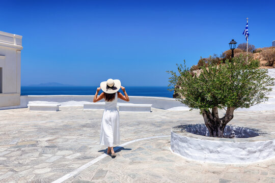 A tourist woman in a white summer dress explores the old town of Folegandros island, Cyclades, Greece