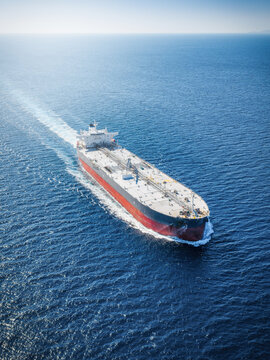 High aerial view of a crude oil tanker ship traveling over the sparkling ocean as a transport concept for fossil fuel