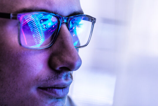 Electronics engineer looks at a glowing computer chip reflection