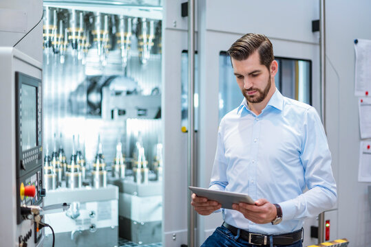 An engineer inspects data on a tablet inside a factory