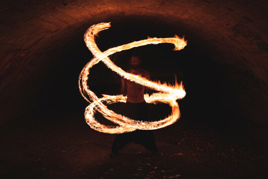 Young man performing fire art in tunnel