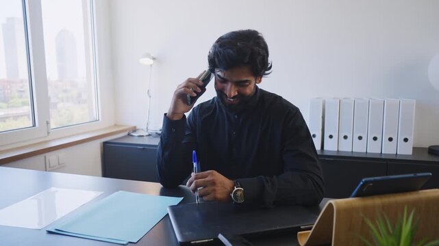 Pakistani Business man in the office. Corporate scene in a modern office with a businessman from pakistan in traditional jubba kandora.