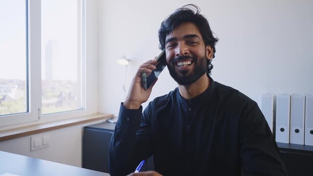 Pakistani Business man in the office. Corporate scene in a modern office with a businessman from pakistan in traditional jubba kandora.