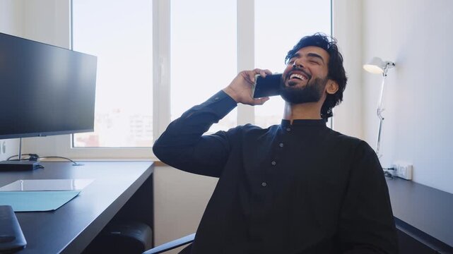 Pakistani Business man in the office. Corporate scene in a modern office with a businessman from pakistan in traditional jubba kandora.