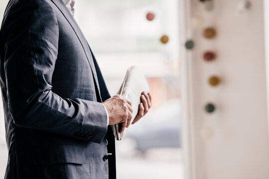 Businessman in cafe holding newspaper, mid section
