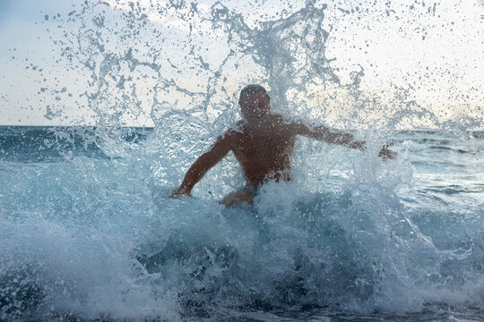 A man swims through a large splashing wave in the Black Sea