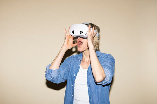 Mature woman in denim shirt experiences exciting virtual reality gaming