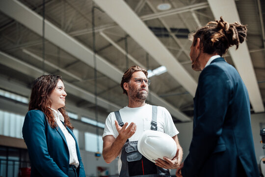 Businesswoman and manager discuss production with a worker indoors