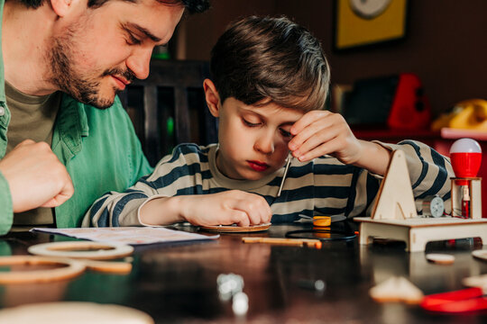 Father and son assembling wooden construction kit at home