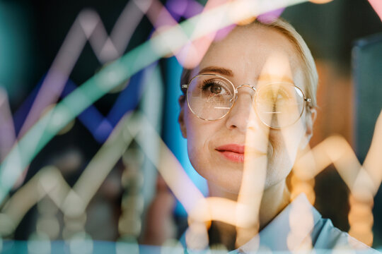 Blonde businesswoman analyzes digital data chart on modern screen