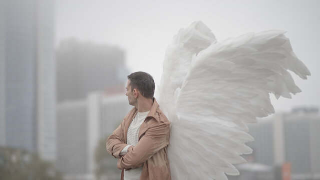Side view of angel man looking at foggy cityscape with text space