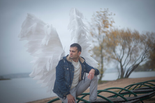 Guardian angel man crouching on lakeside beach in autumn with copy space