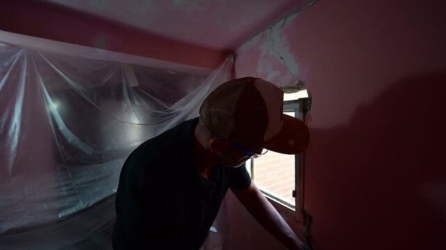 Construction worker demolishing a window frame with a chisel
