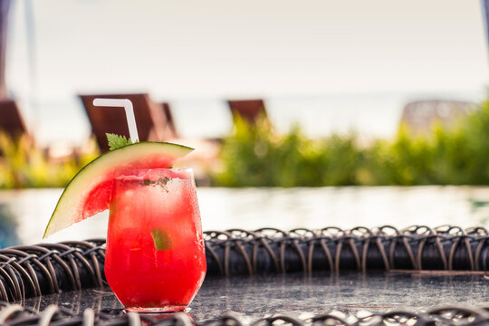 Watermelon soda cocktails on table with blurred poolside and beach background. Summer drinks concept.