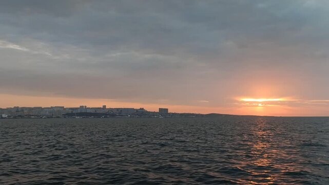Scenic sunset over the sea and coastal city, panning shot