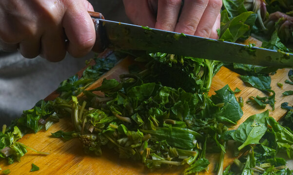 Top view of hands chopping fresh green spinach for traditional Uzbek somsa.