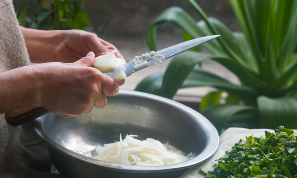 Slicing white onion into a bowl for green somsa preparation.