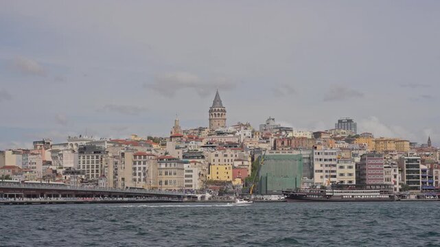 Wide 4K 2x slow motion panorama of the Galata Bridge, Karakoy hillside and Galata Tower seen across the Bosphorus on a cloudy day in Istanbul