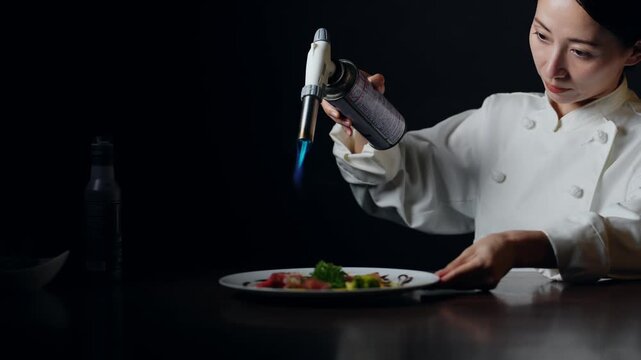 バーナーで料理を炙る女性シェフ。レストラン、調理師、フレンチ、イタリアン、コース、高級、美食、飲食店