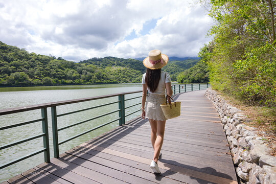 Woman walking on wooden boardwalk by lake in Taiwan