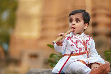indian little boy on traditional wear and playing with flute like little krishna © Niks Ads