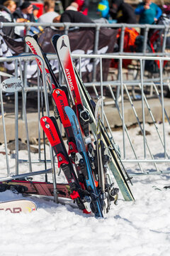 A collection of skis and snowboards parked in the snow at Whakapapa Ski Field, with winter visitors relaxing in the background on Mount Ruapehu, New Zealand