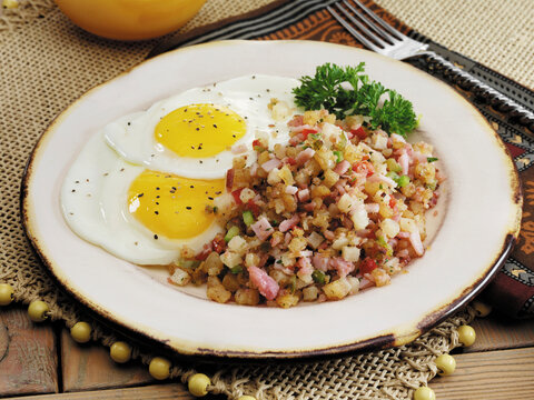 Canadian Bacon hash with fried eggs seasoned with black pepper