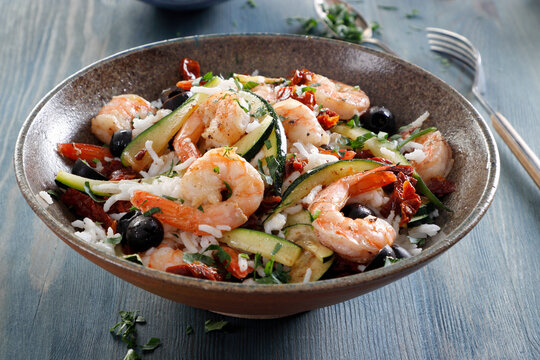Dish with shrimps, rice, olives and zucchini
