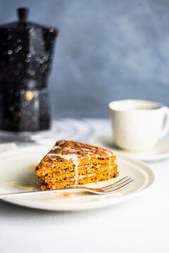 Honey cake slice with cup of coffee cup and stovetop coffee maker