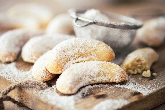 Vanilla crescent biscuits dusted with powdered sugar on a wooden board