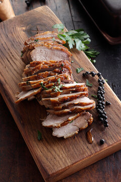 Sliced roasted duck with pepper and parsley on wooden board