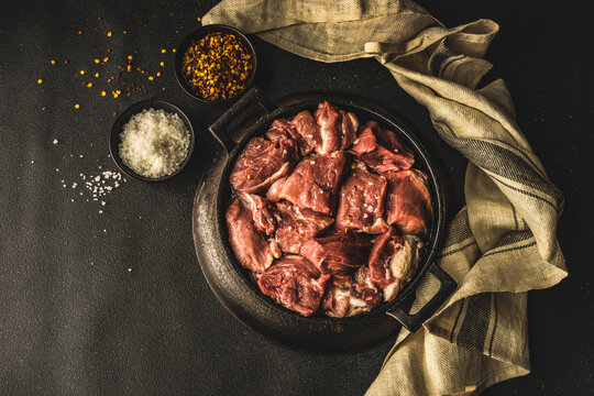 Raw pork meat seasoned with salt and chili flakes in a black dish
