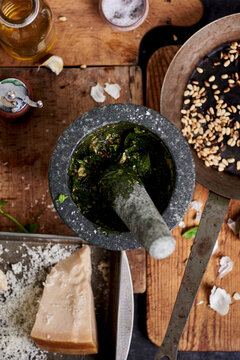 Pesto ingredients crushed in a stone mortar on wooden table