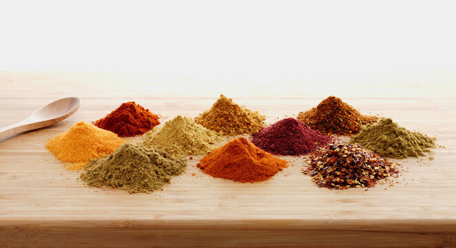 Piles of assorted Mediterranean spices on wooden board