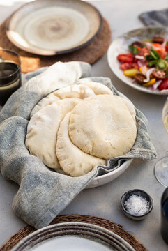 Pita bread in basket with tomato salad and drinks at table setting