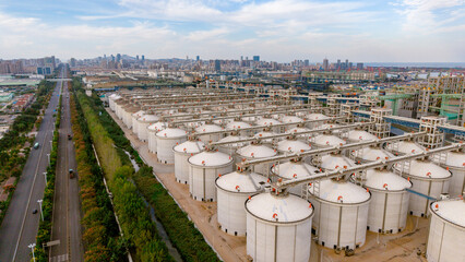 Aerial view of large white industrial oil storage tank farm near city skyline © Zhaorui