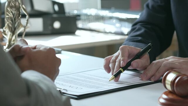 Lawyer explaining legal document and contract terms to a client during a consultation at the law firm with a gavel nearby