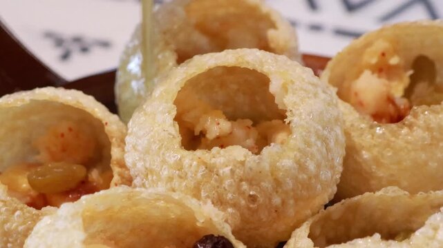 Pouring mint flavored water into traditional Indian panipuri golgappa snack.