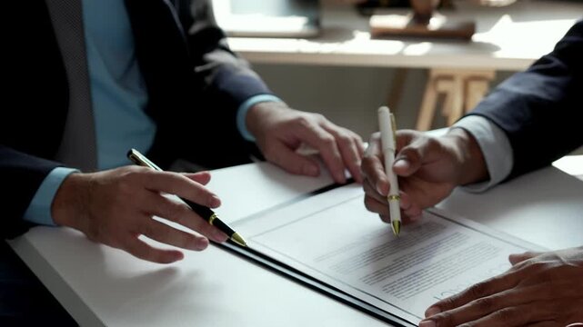 Businessmen discussing and reviewing a legal contract before signing the agreement in a modern corporate office meeting