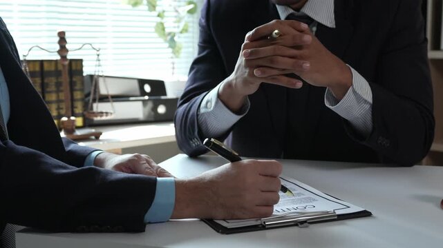 Businessman signing legal contract in law office with lawyer before shaking hands in successful business deal