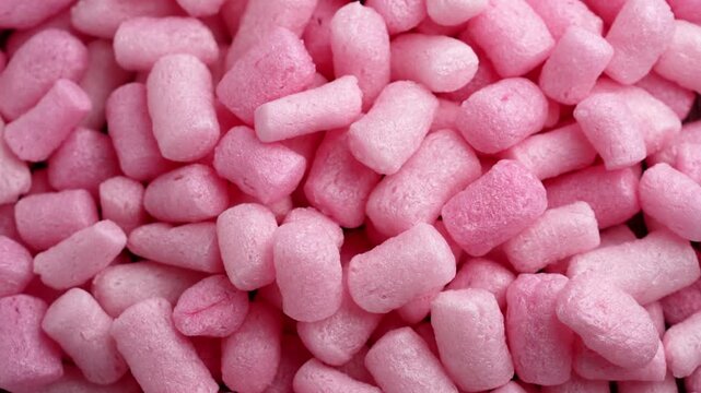 Pink biodegradable packing peanuts filler with porous texture and cylindrical shapes. Sustainable packaging material