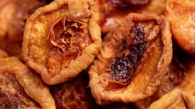 Dried peach halves with wrinkled orange flesh and dark centers. Dehydrated fruit with fibrous texture. Healthy eating ingredient