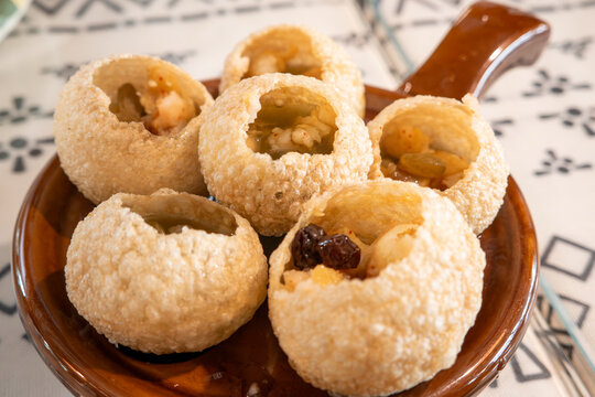 Traditional Indian panipuri golgappa snack served with mint flavored water.