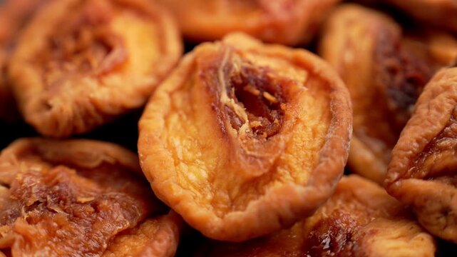 Pile of sweet dried peaches (Prunus persica). Preserved fruit half with wrinkled skin and fibrous texture. Healthy snack