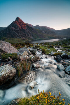Sunset light on Tryfan peak with flowing mountain stream and Llyn Ogwen in Eryri National Park