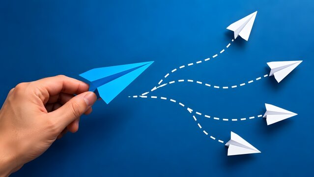 Hand holding a blue paper airplane launching multiple white paper airplanes in different directions conceptualizing strategic distribution and creative communication