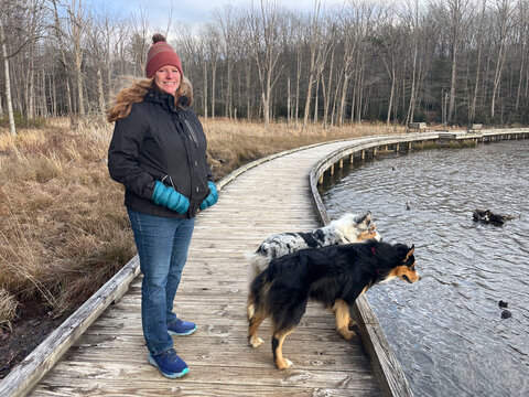 Portrait of smiling woman with two dogs by pond