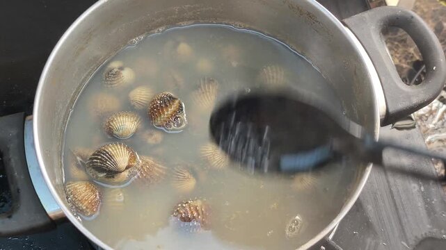 Fresh clams are boiled with garlic and aromatic herbs in a pot. This cooking process enhances rich flavors while removing unwanted fishy odors.