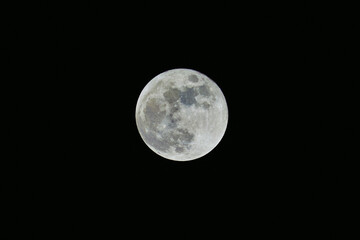 Full moon photographed against a dark black night sky, with visible lunar surface details and large copy space © Ekaterina Pokrovsky