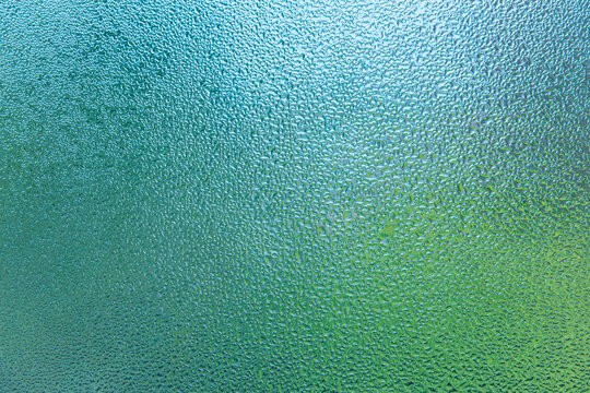 Condensation patterns on glass with green tones
